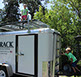 looking up at a child standing atop a large grey revrack tray attached to a enclosed white trailer in a campground setting