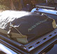 a weatherproof bag attached to small revrack tray atop a gold nissan pathfinder
