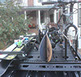 two pair of skis, two snowboards and a mountain bike attached to a small black Revrack tray atop a vehicle in front of a white house