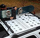 looking down at a man in a black baseball hat and jacket attaches two snowboards to a small revrack using the sliding revrack posts